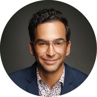 A man wearing a blue jacket and glasses is smiling for the camera. AI generated content